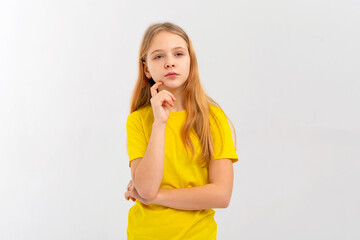 Dreamy nice pretty teen girl touch chin, thought choose decide solve problems dilemmas, wears yellow tshirt. Indoor studio shot on white background