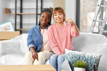 Obraz premium moving, people and real estate concept - happy smiling women with keys at new home