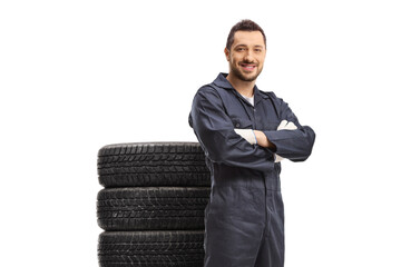 Smiling car mechanic posing with a pile of tires behind him
