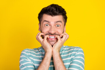 Closeup photo of young handsome guy bite fingers nervous deadline work isolated on yellow color background