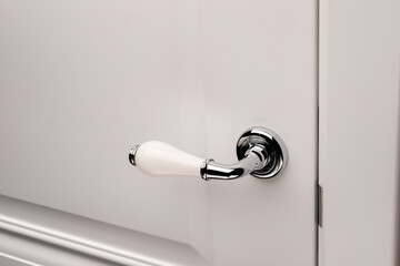 Close up of stylish and elegant door knob or handle on white door.