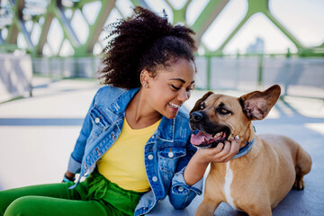 Multiracial girl sitting and resting with her dog outside in the bridge, training him, spending...
