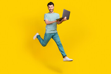 Full size photo of boss guy run with laptop wear t-shirt jeans boots isolated on yellow color background