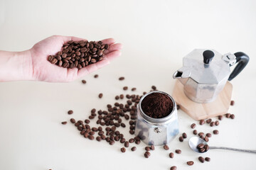 A hand holding Coffee beans with Mokapot and coffee beans on the ground. Ingredient for mokapot ...