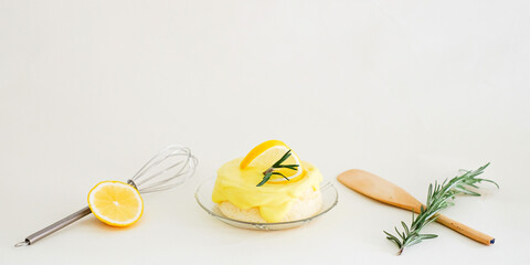 A round minimal sweet, sour and tasty Lemon chiffon or sponge cake. Decorated with rosemarry, whisk, paddle and lemon slice in  a white background. Use for homemade minmal cafe style. Wide screen.