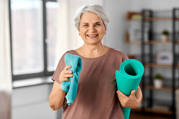 sport, fitness and healthy lifestyle concept - happy smiling senior woman with yoga mat and towel at home