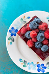 A piece of cake with poppy seeds and berry jelly, cake on a plate decorated with juicy raspberries and blueberries