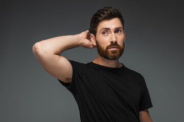 portrait of puzzled man in black t-shirt looking away isolated on grey.