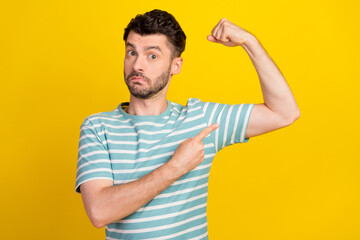 Photo of young attractive sporty man showing his biceps hobby after work fit serious isolated on bright yellow color background