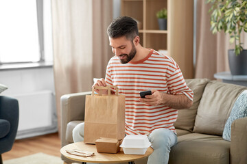 communication, leisure and people concept - man using smartphone for takeaway food order check up...
