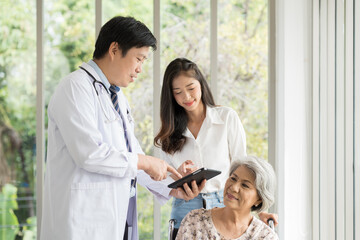 Doctor, nurse and elderly patient woman sit on wheelchair. Male doctor visit elderly asian woman on wheelchair at the hospital © amorn