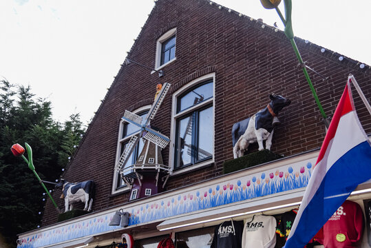 Volendam, Países Bajos ; 07 26 2022: detalle de la parte superior de un edificio holandés, con un molino decorativo, dos vacas y tulipanes adornando la fachada.