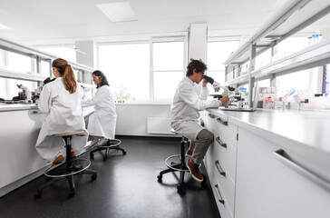 science research, work and people concept - international group of scientists with microscopes working in laboratory