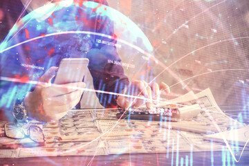 Double exposure of man's hands holding and using a digital device and forex graph drawing. Financial market concept.