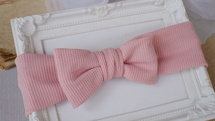 Bow headband made out of knit fabric with beautiful texture in soft peach color. A hair accessory with bow in front.