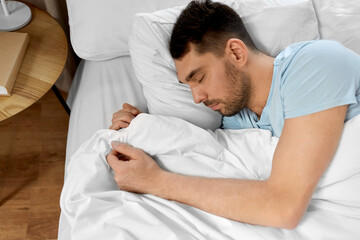 people, bedtime and rest concept - man sleeping in bed at home