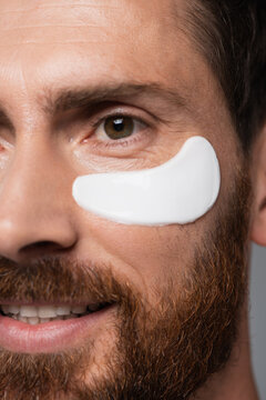close up view of happy bearded man with moisturizing eye patch.