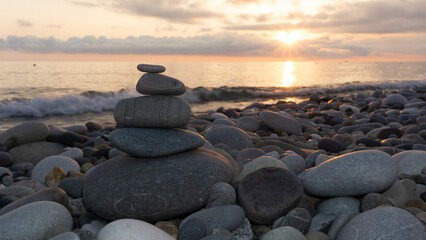 Stack of zen stones on the beach at sunset, beautiful seascape. Made of stone tower as rest balance vacation concept.