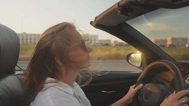 girl with glasses drives a cabriolet