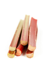 Rhubarb sticks on a white background, selective focus. Red-green fresh stems.
