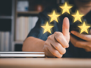 Man's hand thumbs up to rating score or survey feedback. Five stars virtual screen shown. Rating or...