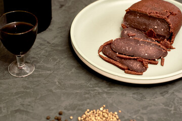 sliced basturma on a plate next to a bottle of wine and a glass