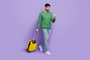 Full size photo of young latin arabian man hold telephone online booking dressed stylish green clothes isolated on purple color background