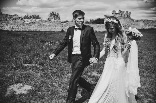 The bride and groom with a wedding bouquet in hands on the nature. Portrait of an attractive couple in country. Wedding ceremony. Newlyweds getting married outdoors. Black and white photo.