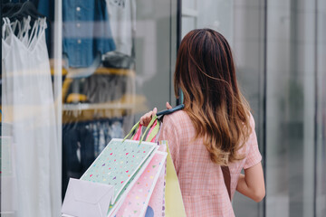 Shopper customer asian woman using smartphone at shopping mall outside, cashless technology payment shopping in the city