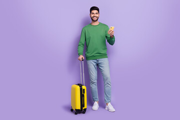 Full body photo of young latin arab guy hold device flight airport check in wear stylish green clothes isolated on purple color background