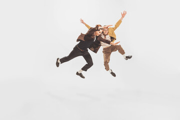 Portrait of two stylish men, friends spending time together, posing in a jump isolated over white studio background