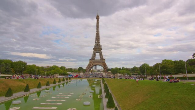 Eiffel Tower on Champs de Mars in Paris, France. Blue cloudy sky at summer day with green lawn