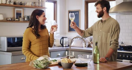 Young couple cooking, drinking wine and preparing a meal together while bonding, having fun and talking in home kitchen. Smiling, happy and caring husband and wife making healthy food for date night