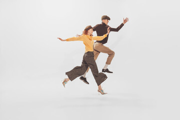 Fototapeta na wymiar Portrait of young man and woman in stylish clothes posing in a jump isolated over white studio background. Autumn fashion collection