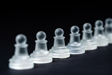 opaque glass chess pawn row on black background, selective focus, closeup
