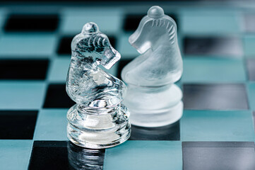 two opponent glass chess knights on a glass chess board, black background