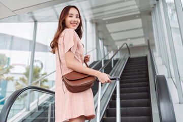Smiling of asian woman hold suitcase going travel trip in the airport terminal for go to destination, Female travel lifestyle concept.