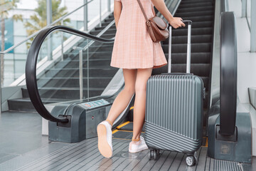 Close up legs of asian woman hold suitcase going travel trip in the airport terminal for go to destination, Female travel lifestyle concept.