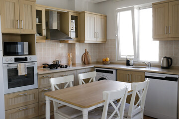 Stylish wooden kitchen with a window, built-in appliances and small beige tile. Close up, copy space, background.
