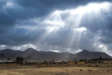 View of Los Ajaches from Puerto del Carmen in Lanzarote with sunbeams through the clouds