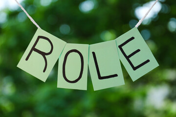 Notes with word Role hanging on blurred background
