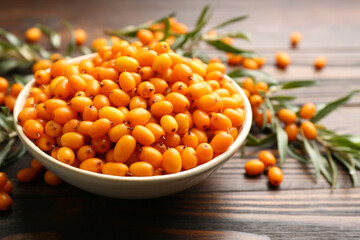 Fresh ripe sea buckthorn in bowl on wooden table, closeup