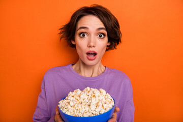 Photo of impressed nice lady hold big plate popcorn open mouth look camera isolated on orange color background