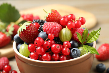 Mix of different fresh berries in bowl on table, closeup