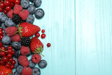 Different fresh berries on light blue table, flat lay. Space for text