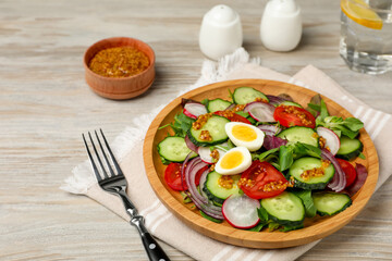 Tasty salad with vegetables and quail eggs on wooden table