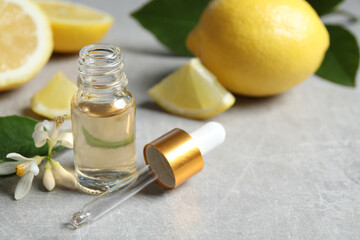 Citrus essential oil, flower and lemons on light table. Space for text