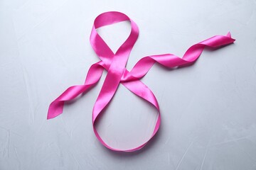 8 March greeting card design with pink ribbon on light grey background, top view. International...
