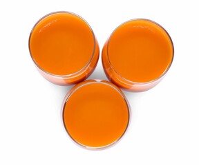 Three glasses of fresh carrot juice on white background, top view