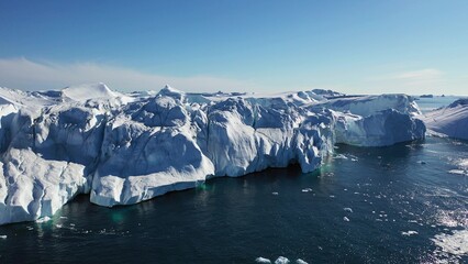 Aerial view from a drone of massive icebergs floating off the coast of a glacier on a sunny day in Disko Bay off the coast of Ilulissat, Greenland.